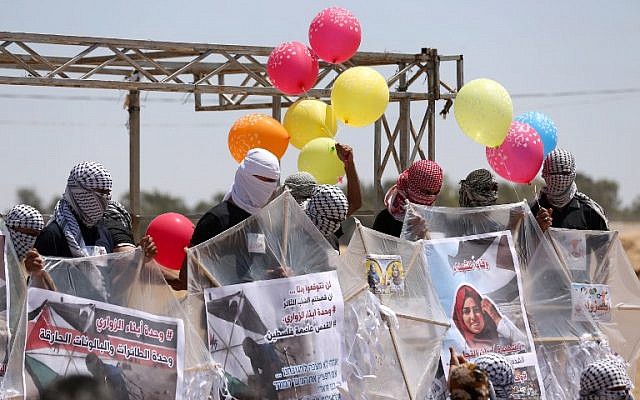 Palestinians load kites and balloons with flammable material in order to fly toward Israel, at the Israel-Gaza border in al-Bureij, central Gaza Strip, on June 14, 2018. (AFP Photo/ Mahmud Hams)