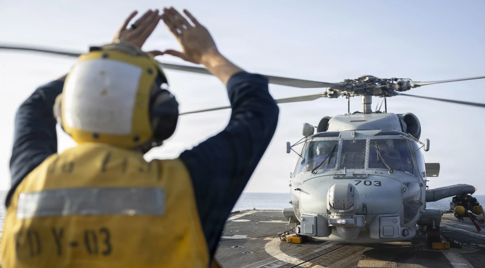 A U.S. sailor, assigned to Arleigh Burke-class guided-missile destroyer USS Delbert D. Black, directs an MH-60R Sea Hawk helicopter,