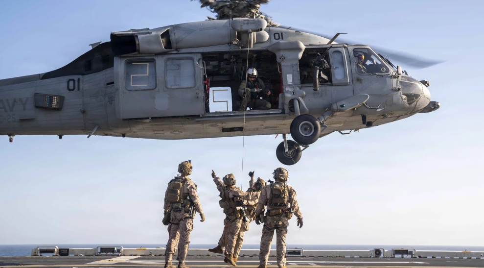 U.S. Sailors and Marines conduct live-hoist training with an MH-60S Sea Hawk helicopter on the flight deck of America-class amphibious assault ship USS Tripoli, April 15, 2026. Credit: U.S. Navy.