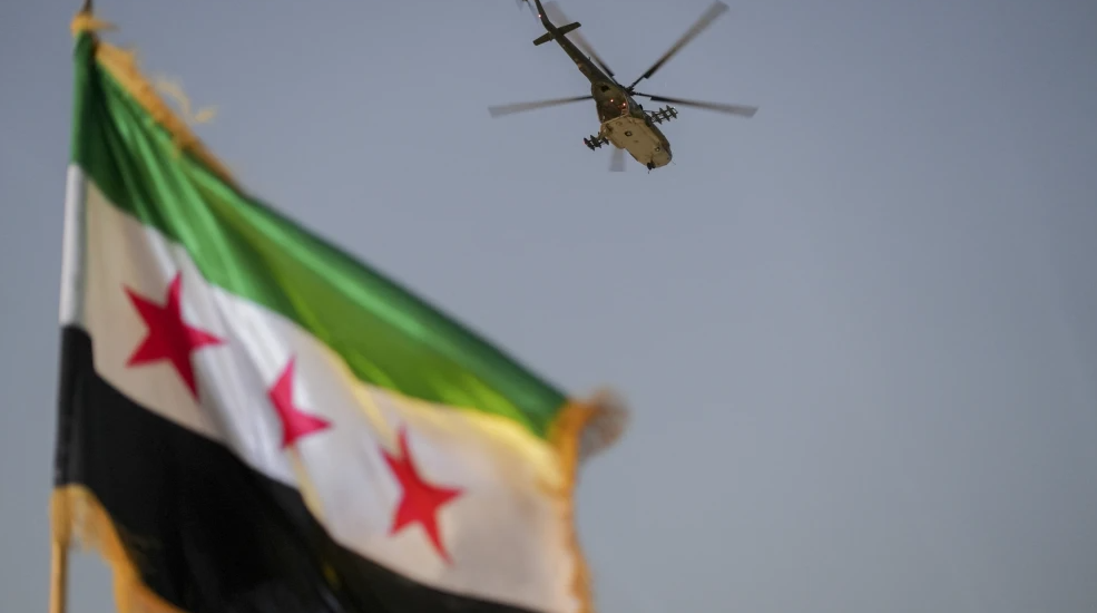 A military helicopter flies above a Syrian flag during the Syria Summer Family Festival in Damascus, Syria, Aug. 9, 2026. Photo by Omar Albam/Middle East Images/AFP via Getty Images.