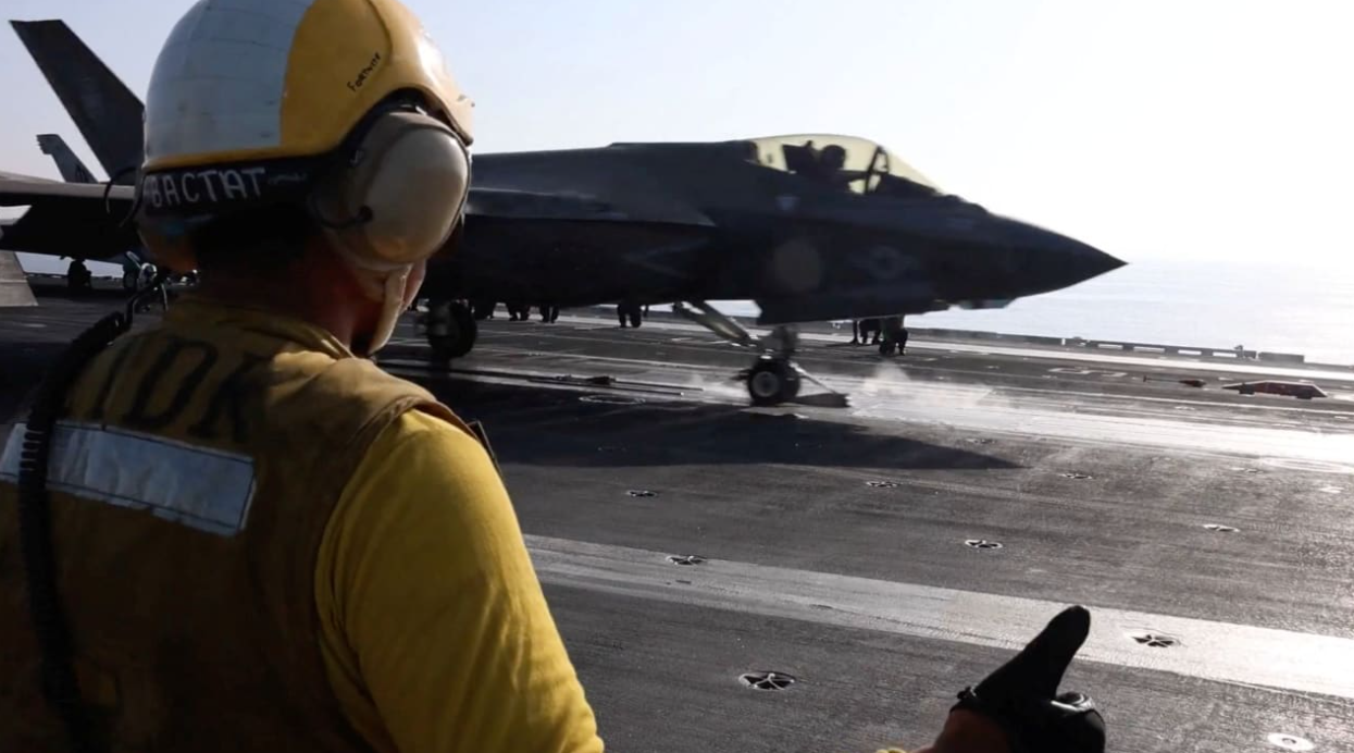 A screengrab from a video released by CENTCOM shows a flight deck crew member signaling an F‑35 jet on an aircraft carrier, in this image obtained from social media released on February 28, 2026 (photo credit: US CENTCOM)