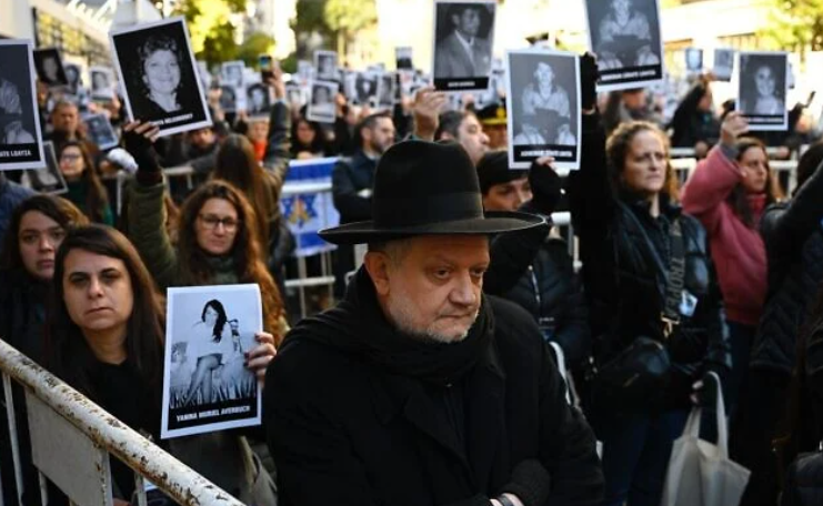 People hold pictures of victims during a ceremony to commemorate the 31st anniversary the AMIA bombing attack which left 85 dead and more than 300 wounded, in Buenos Aires, Argentina, on July 18, 2025. (Luis ROBAYO / AFP)