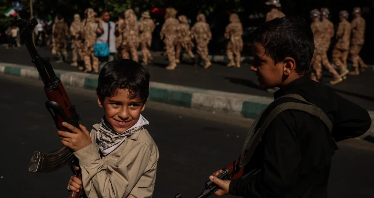 Young children carrying military-style weapons are seen during street parades conducted by military forces of the Islamic Republic of Iran, who provide military training to supporters in preparation for a potential conflict with the United States and Israel, on September 18, 2026, in Tehran, Iran. (photo credit: Meghdad Madadi ATPImages/Getty Images)