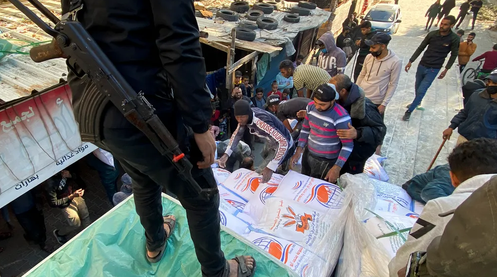 Palestinians unload sacks of wheat from a humanitarian aid truck into a grocery store guarded by Hamas fighters in Rafah, in the Gaza Strip.AP Photo