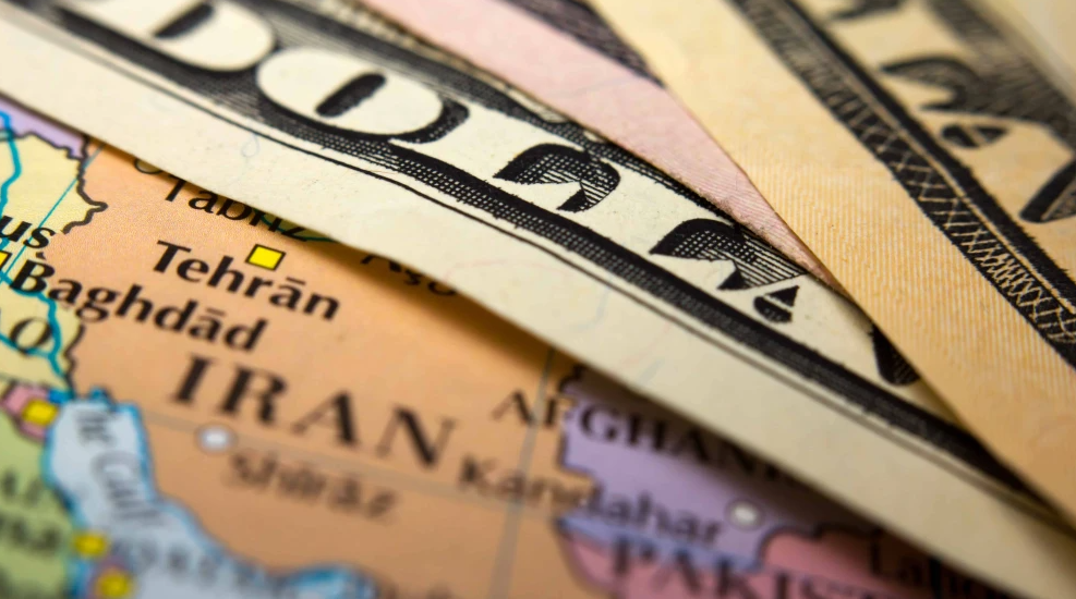 Dollar bills on top of a map of Iran. Credit: corlaffra/Shutterstock.